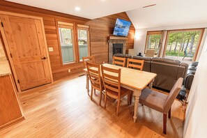 A wooden interior with a dining area, a fireplace, and a sofa.