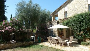 A stone building with a patio area featuring a table and chairs under a large umbrella. - Charming cocoon for 4p in nature, space, infinity pool (Châteauneuf-Grasse)
