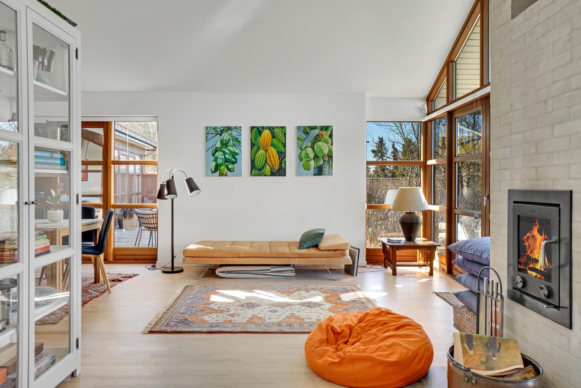 A modern living room with a sofa, bean bag, and a fireplace. There are bookshelves, a lamp, and artwork on the wall.