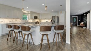 A spacious kitchen with a large island, bar stools, stainless steel appliances, and pendant lighting. - Luxurious Chalet in Blakeslee: Game Room, Hot Tub, Lake Access, Fire pit (Blakeslee)