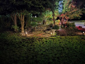 Ein Garten mit einer Holzbank, einer Steinmauer und verschiedenen Pflanzen.