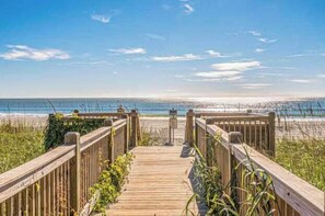 Un muelle de madera que conduce a una playa bajo un cielo despejado.
