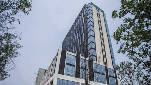 A modern high-rise building with a glass facade and a prominent corner entrance. - Greentree Inn Qinhuangdao Haigang District Railway Station Square Express Hotel (Qinhuangdao)