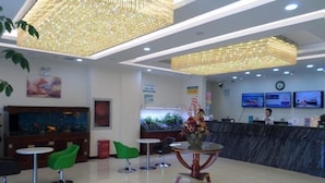 A hotel lobby with a reception desk, green chairs, a round table, and a large aquarium. - Greentree Inn Qinhuangdao Haigang District Railway Station Square Express Hotel (Qinhuangdao)
