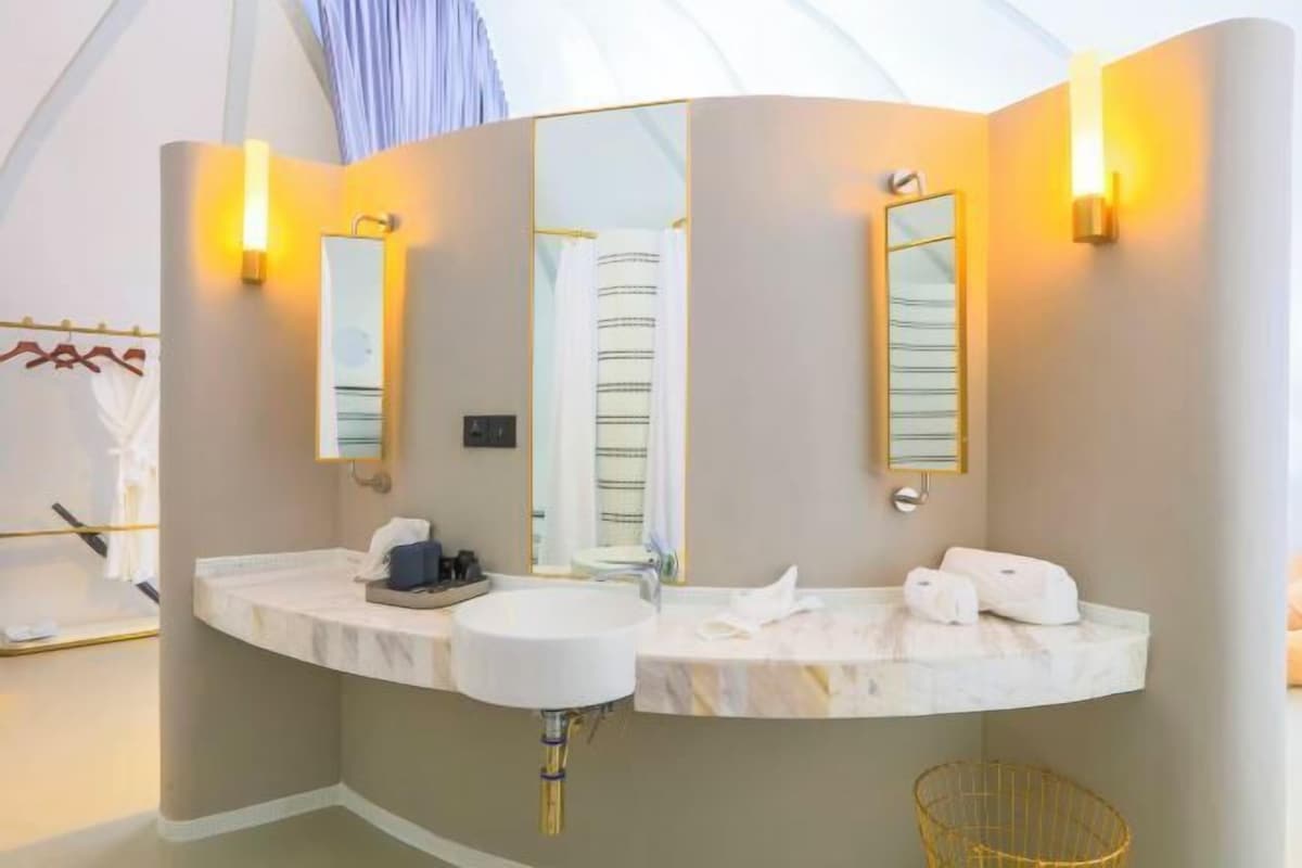 A modern bathroom with two sinks, mirrors, and wall-mounted lights.