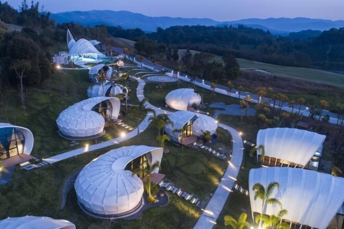 A resort with dome-shaped accommodations, pathways, and a mountainous backdrop.