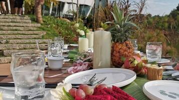 A table set for a meal with plates, glasses, and tropical fruits like pineapple and dragon fruit.