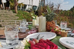 A table set for a meal with plates, glasses, and tropical fruits like pineapple and dragon fruit. - Xishuangbanna Visible Zeqi Tent Hotel (Menghai)
