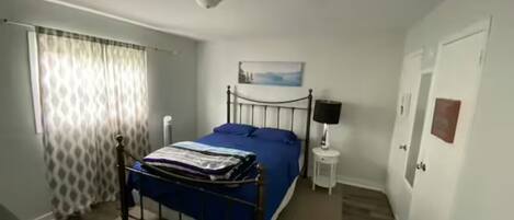 A bedroom with a bed, a bedside table, a lamp, and a painting on the wall.