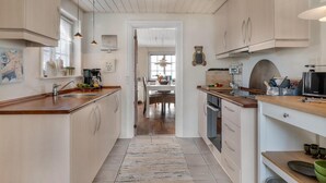 A modern kitchen with light wood cabinets, a central island, and a dining area in the background. - Lovely home in Pandrup with WiFi (Pandrup)