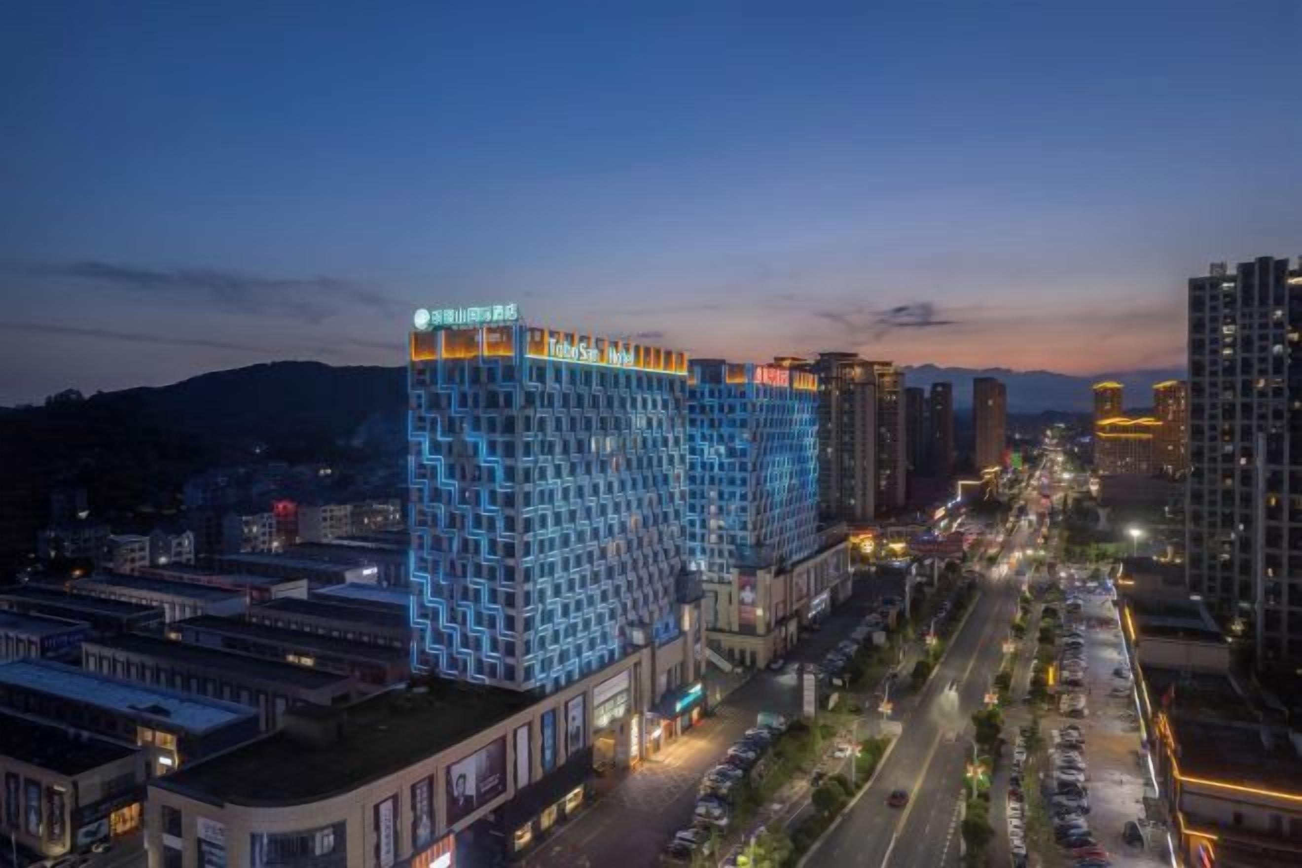 Ein Hochhaus-Hotel mit mehreren Etagen, einer auffälligen Beschilderung obenauf und einer belebten Straße im Vordergrund.
