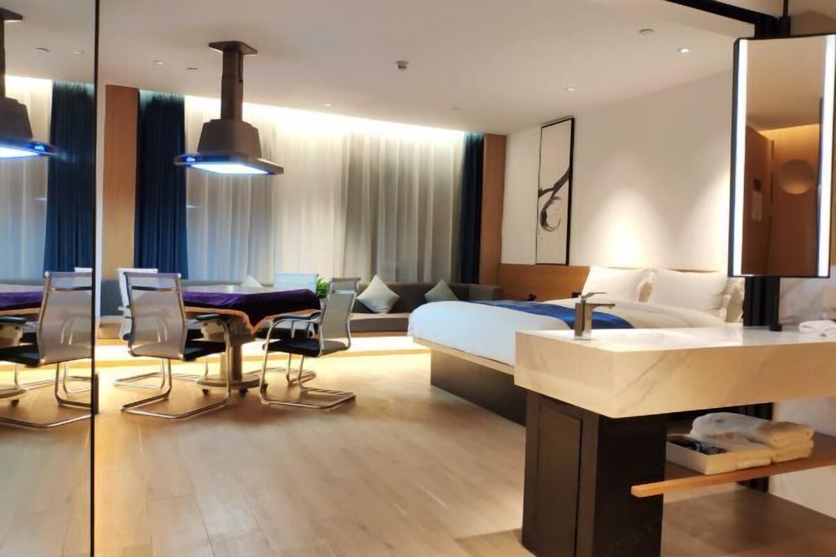 Une chambre d’hôtel moderne dotée d’un grand lit, d’un bureau avec une chaise, d’un miroir et d’une salle de bain comprenant un lavabo et un porte-serviettes.