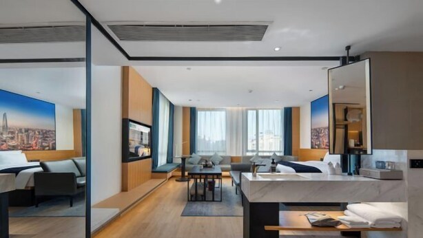 Ein modernes Hotelzimmer mit Bett, Schreibtisch, Sofa und großem Fenster.
