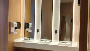 Un baño moderno con dos lavamanos, un espejo grande y secamanos.