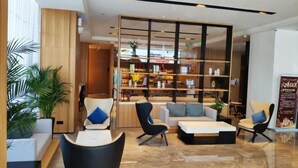 Eine moderne Lobby mit Sitzbereichen, einer Rezeption und einem Bücherregal.