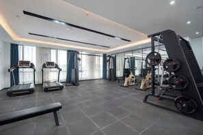Une salle de sport moderne équipée de tapis de course, d’un banc et de matériel de musculation.