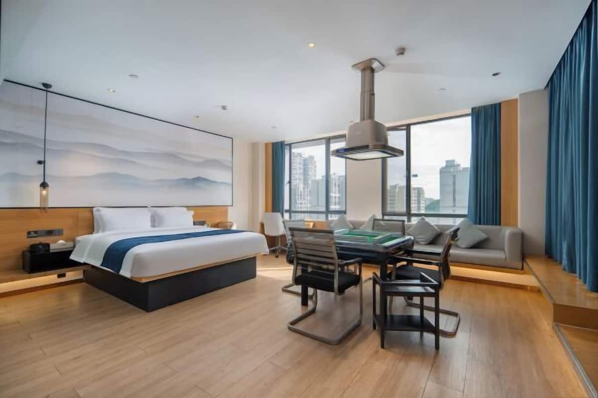 Ein modernes Hotelzimmer mit einem großen Bett, einem Esstisch und einer Sitzecke.