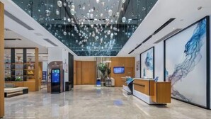 Eine moderne Lobby mit einer Rezeption, einer digitalen Informationskiosk und einem großen abstrakten Gemälde an der Wand.