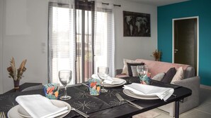 Un coin repas avec une table dressée pour deux personnes, agrémenté d’une nappe noire, d’assiettes blanches et de verres transparents.