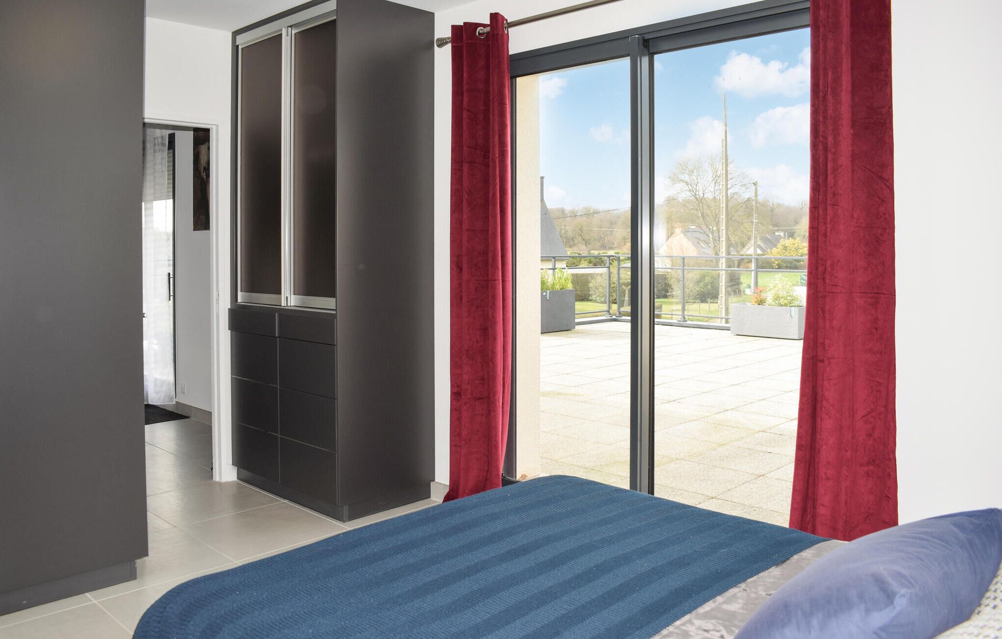 A bedroom with a bed, a wardrobe, and a sliding glass door to a balcony.
