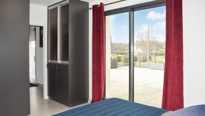 Une chambre avec un lit, une armoire et une porte-fenêtre coulissante donnant sur un balcon.