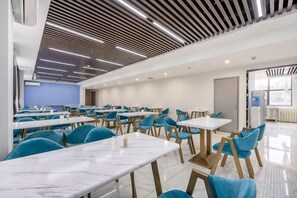 A modern dining area with tables and chairs, a ceiling with linear lighting, and a blue accent wall. - The Sleep Ziihome Hotel (Guiyang)