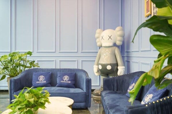 Una habitación con dos sofás azules, una mesa de centro blanca y una gran estatua decorativa de un oso.
