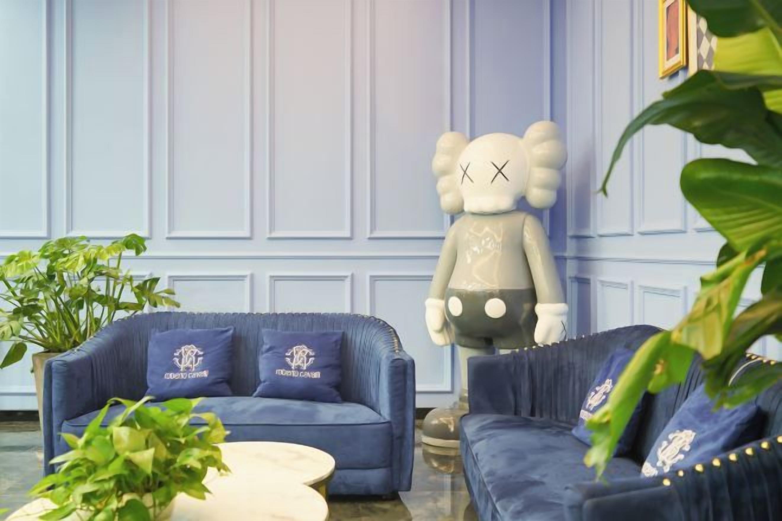 Una habitación con un sofá azul, una mesa redonda blanca y una figura decorativa de un oso.
