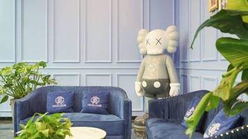 Una habitación con un sofá azul, una mesa redonda blanca y una figura decorativa de un oso.