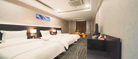 Une chambre d’hôtel avec deux lits, un bureau, un miroir et un climatiseur fixé au mur.
