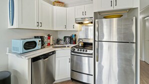 A compact kitchen with white cabinets, a stainless steel refrigerator, a microwave, a stove, and a dishwasher. - Family Beachfront Retreat: Walk to Coligny Plaza with Side Ocean Views (Hilton Head Island)