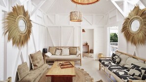 Um quarto espaçoso com um sofá de madeira, uma mesa de centro de madeira e um espelho grande com moldura em forma de sol.