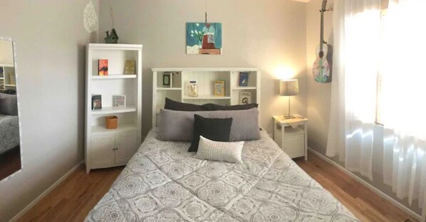 A bedroom with a bed, a nightstand, a bookshelf, and a guitar hanging on the wall. - Perfect Location! Perfect House! Hot Tub, Fire Pits, Rec Room, Bikes, Family Fun (Colorado Springs)