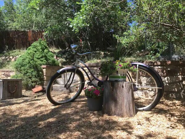Uma bicicleta estacionada ao lado de um toco de madeira com um vaso de flores.