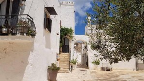 Une rue étroite bordée de bâtiments blancs, avec un escalier et des plantes en pot.