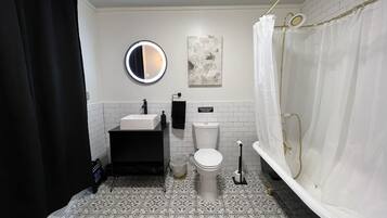 Ein Badezimmer mit schwarzem Waschtisch, weißem Waschbecken und einer weißen Toilette.