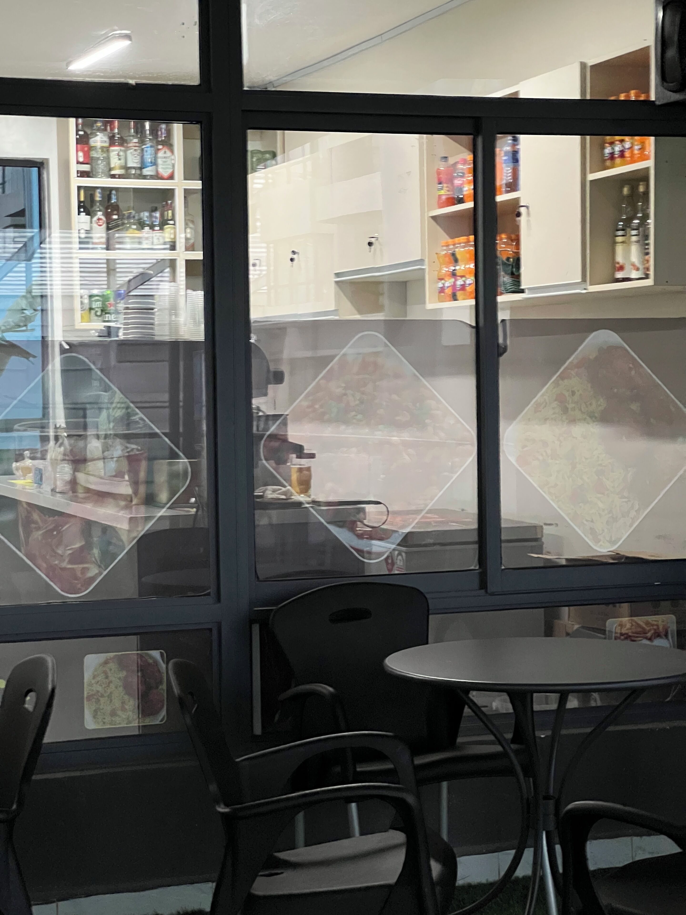 A restaurant interior with a counter, chairs, and a view through a glass partition.