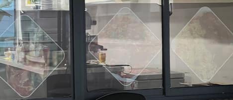 A restaurant interior with a counter, chairs, and a view through a glass partition.