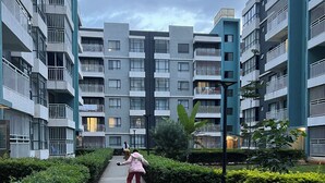 A pathway flanked by modern apartment buildings with balconies, leading towards a distant building. - Indesign Studio  (Syokimau)