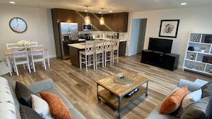 Un salon moderne comprenant un ensemble de canapés, une table basse et un coin repas avec des chaises et une table.