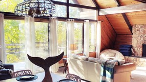 Un loft espacioso con techo alto, ventanas grandes, un comedor con un centro de mesa con forma de ballena y una zona de estar acogedora con chimenea de piedra.