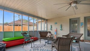 A covered patio with wicker furniture, a green boat, and a red boat.
