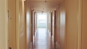 Ein langer, schmaler Hotelkorridor mit Holzdielen und Türen an beiden Seiten.
