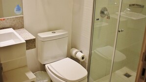 Ein Badezimmer mit Toilette, Waschbecken und einer Duschkabine aus Glas.