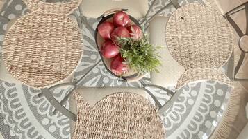 A round table with woven placemats and a central decorative bowl with apples and greenery.