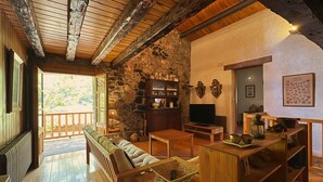 Un interior rústico con pared de piedra, muebles de madera, un televisor y una zona de estar acogedora.