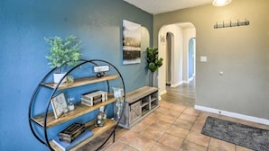 A hallway with a blue wall, a wooden bench, and a metal shelf unit with various decorative items. - Spacious, Cozy 3 Bedroom 2 bath North End Home (Tacoma)