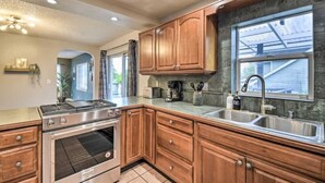 A kitchen with wooden cabinets, a stainless steel stove, and a large window. - Spacious, Cozy 3 Bedroom 2 bath North End Home (Tacoma)