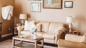 A cozy living room with a wooden ceiling, beige sofas, a coffee table, and framed pictures on the wall. - 3bdrm, 3bath in forest,  12 min to downtown Sequim,Wifi, Fire pit, Sauna, Hottub (Sequim)
