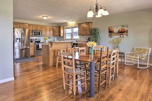A kitchen with wooden cabinets, stainless steel appliances, and a dining area with a wooden table and chairs.